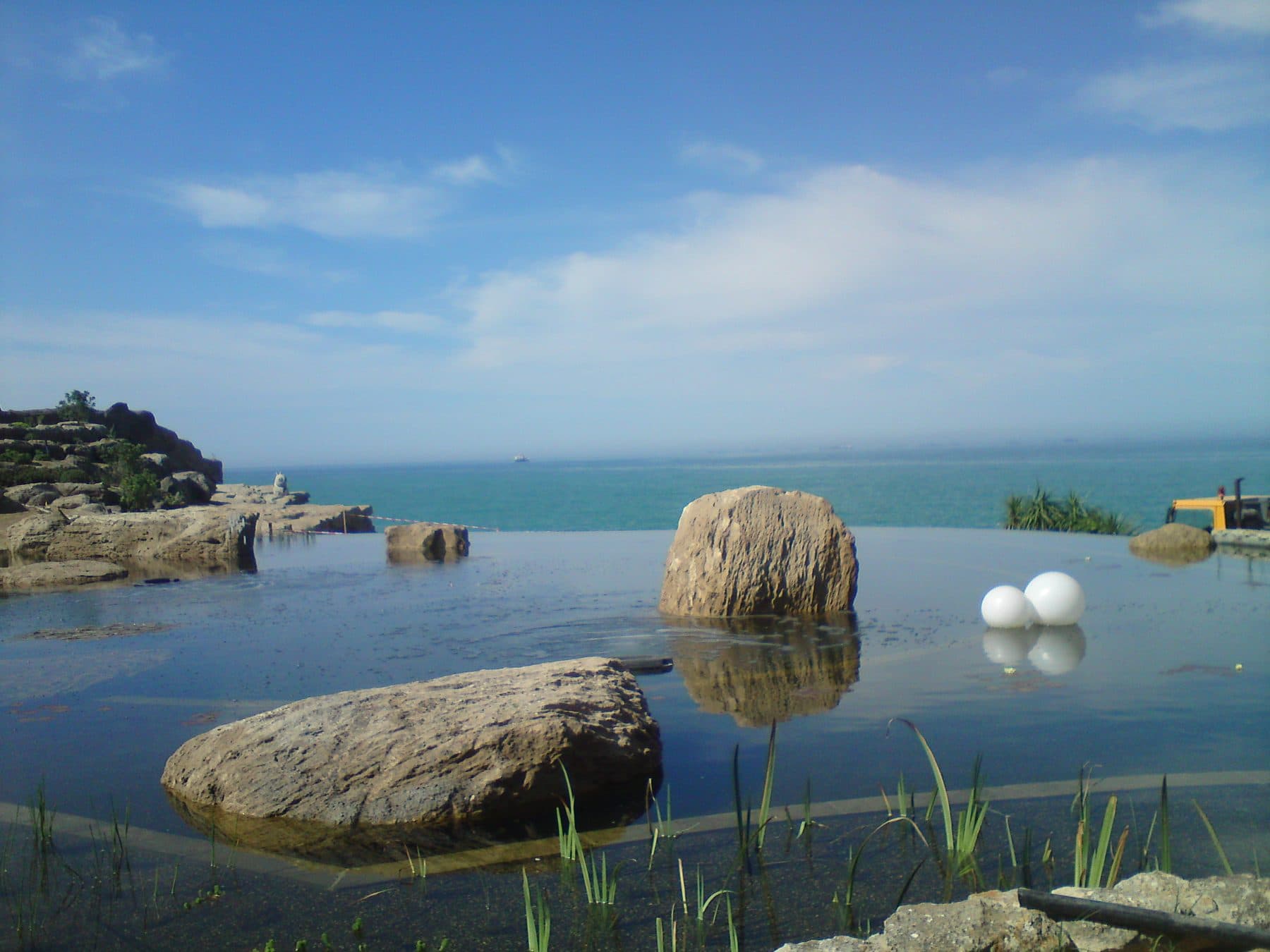 A natural swimming pond set among boulders with the sea beyond