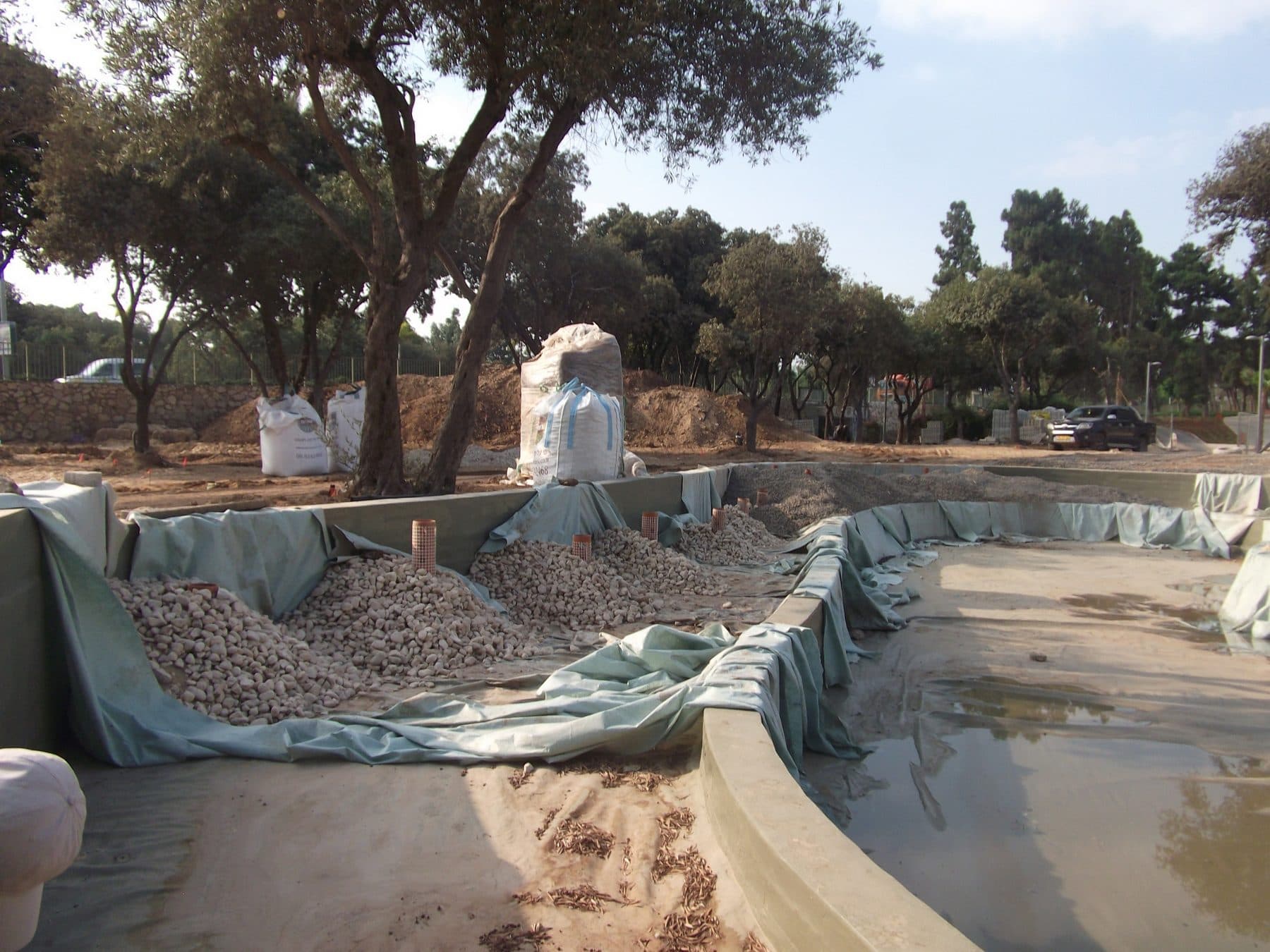 A constructed-wetland basin part-built, with the liner laid and gravel media going in
